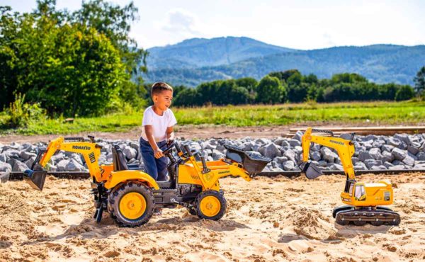 Children playing with Falk Toys Komatsu 2086N pedal backhoe loader outdoors